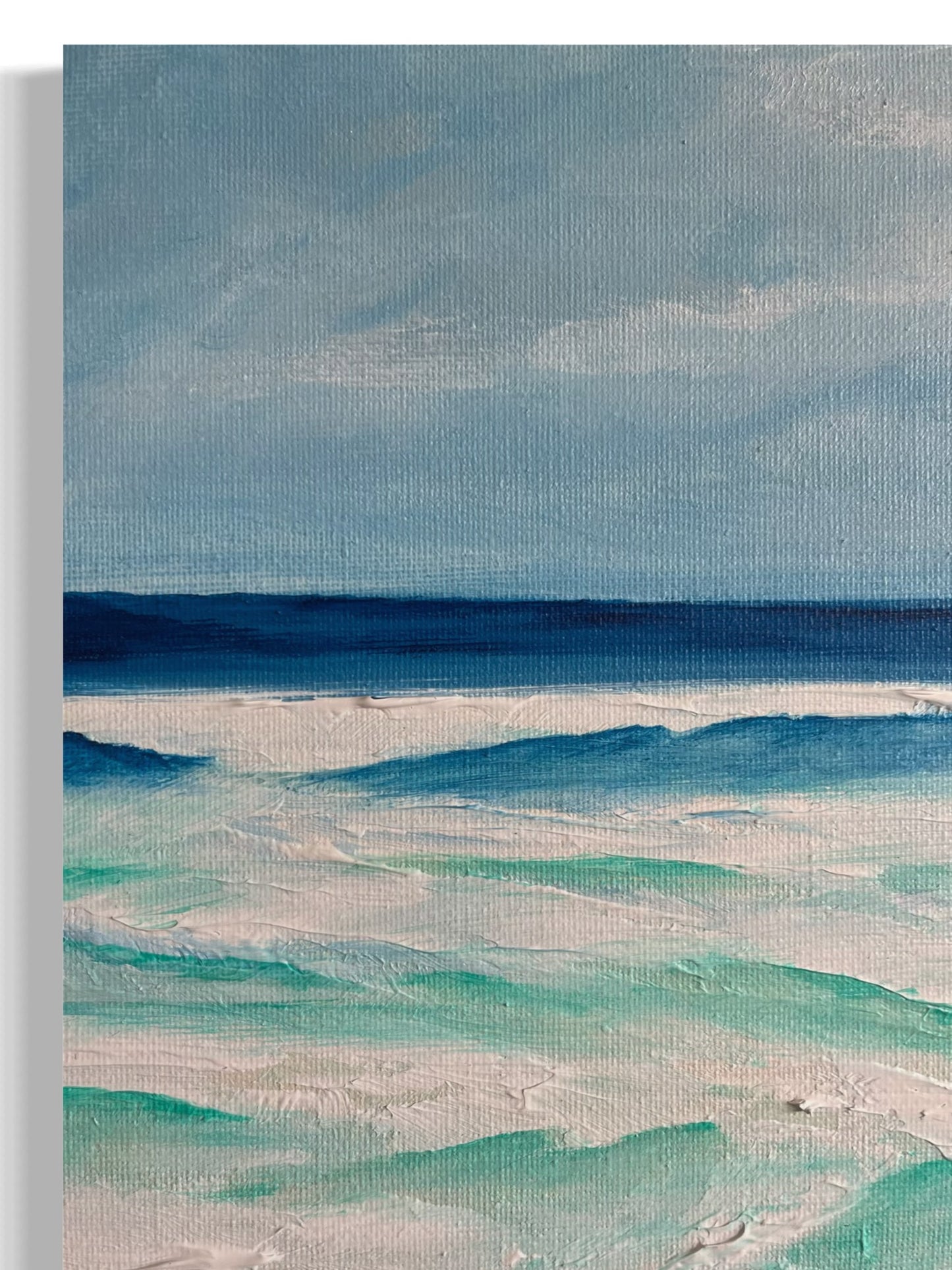 Original hand painted acrylic painting on canvas panel of the ocean off Torquay, with rolling waves crashing against the shore. The vibrant blue and green tones evoke the power and beauty of the sea, while soft whites capture the foam and movement of the water, set against a tranquil coastal sky close-up.