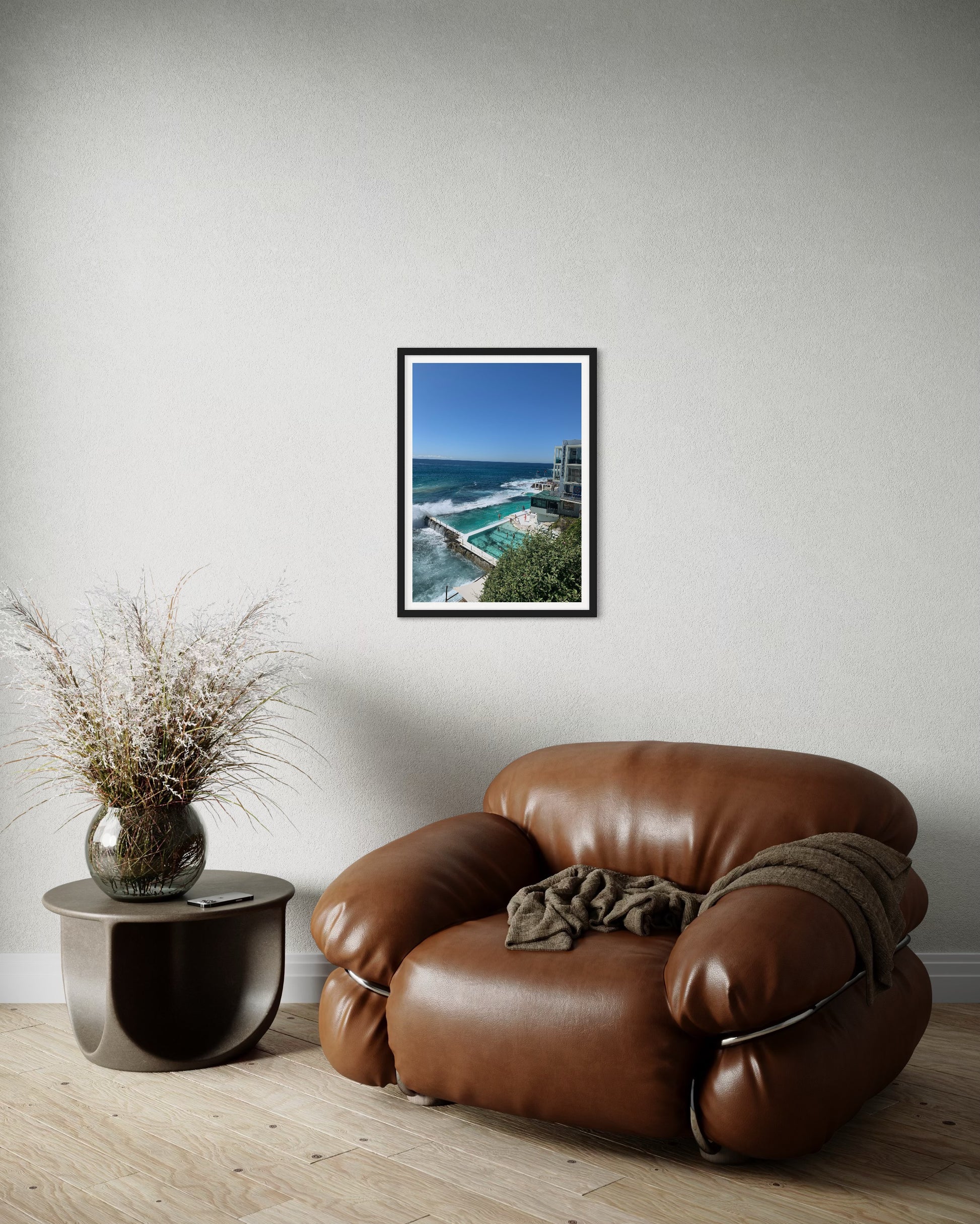A high-quality photograph of the iconic Icebergs Pool at Bondi Beach, New South Wales (NSW), showcasing the stunning contrast between the vibrant blue waters of the pool and the crashing waves of the ocean. The image captures the beauty of the pools set against the rugged coastal landscape, with the clear sky and beach in the background. Printed on premium material for a refined and elegant finish, this photograph is a sophisticated depiction of one of Australia's most famous swimming spots.